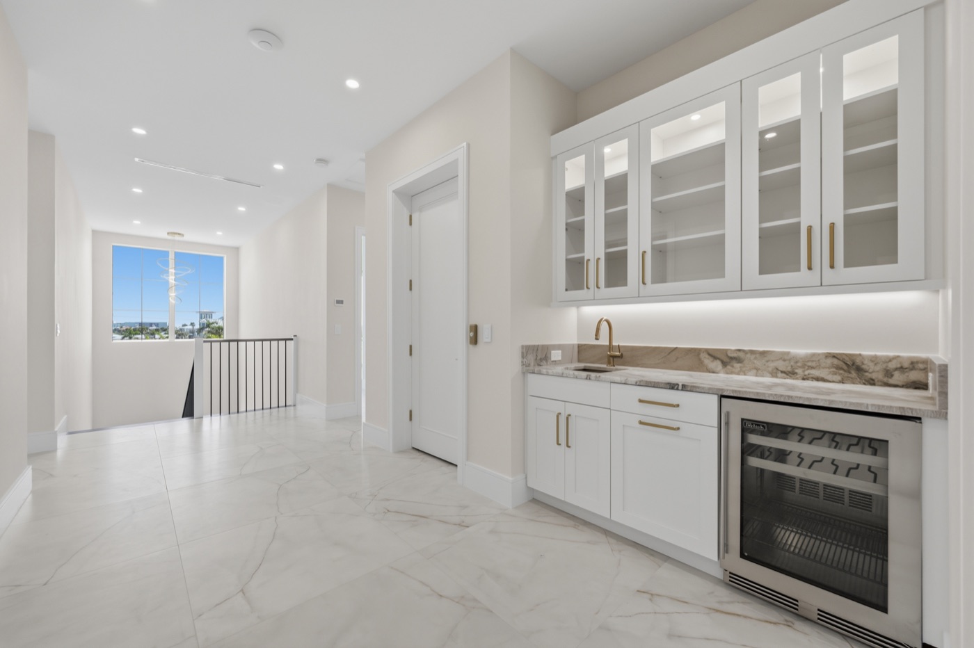 Butler's wet bar with white shaker cabinetry, brass hardware and gold-veined marble — Coastal Residence